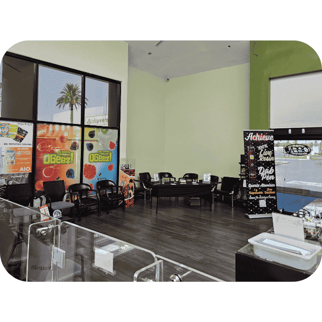 Interior View of All Cannabis Dispensary Glass jars filled with cannabis buds displayed on illuminated counters inside a modern dispensary, with a customer at the entrance.